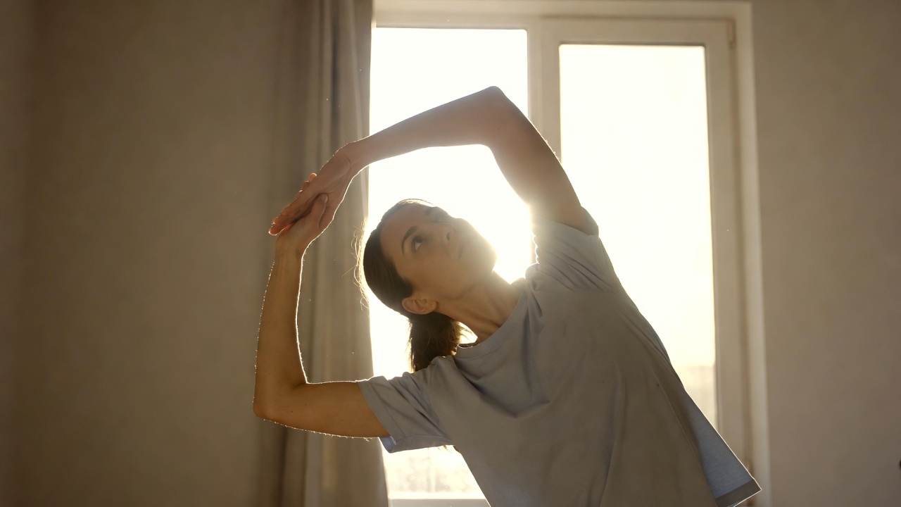 Person doing morning stretch near window after waking up early